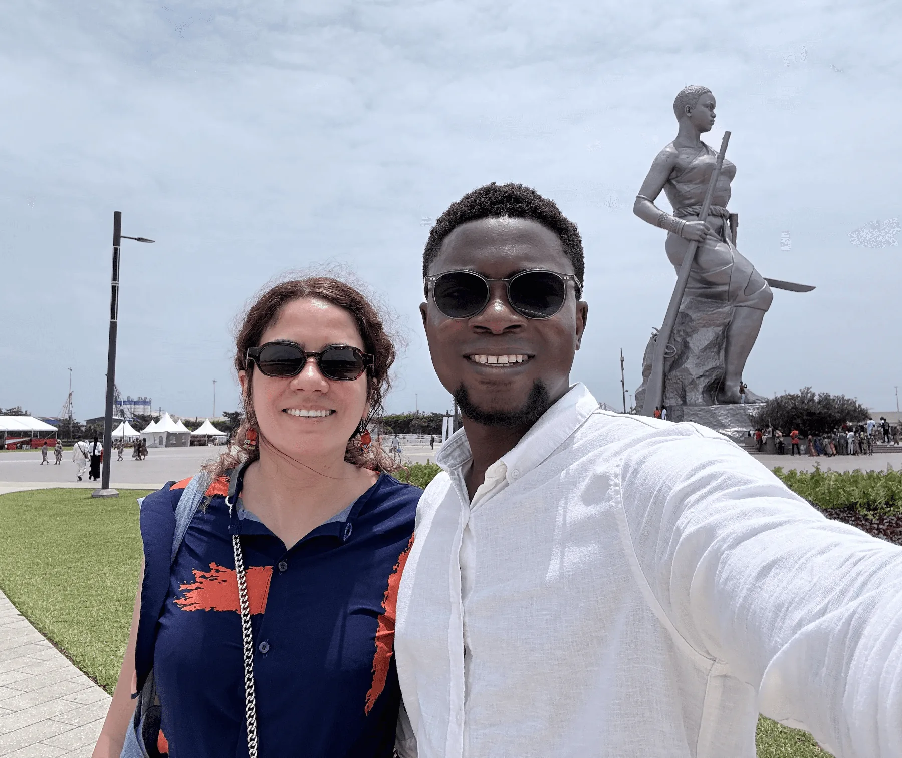 Hajer and Ramdane in front of a large bronze monument in Bénin